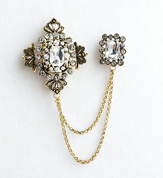 Decorative brooch with gemstones and chain on a white background