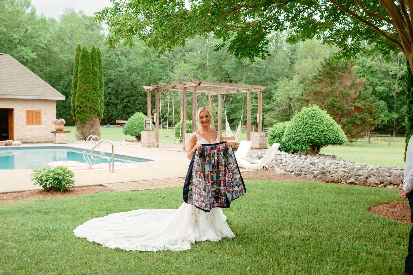 Woman in wedding dress holding a suit jacket displaying the custom picture collage suit lining outdoors with a pool and garden in the background
