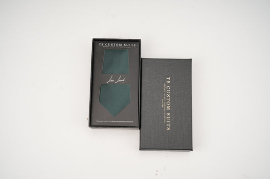 Green tie in box with 'TC Custom Suits' branding on a white background