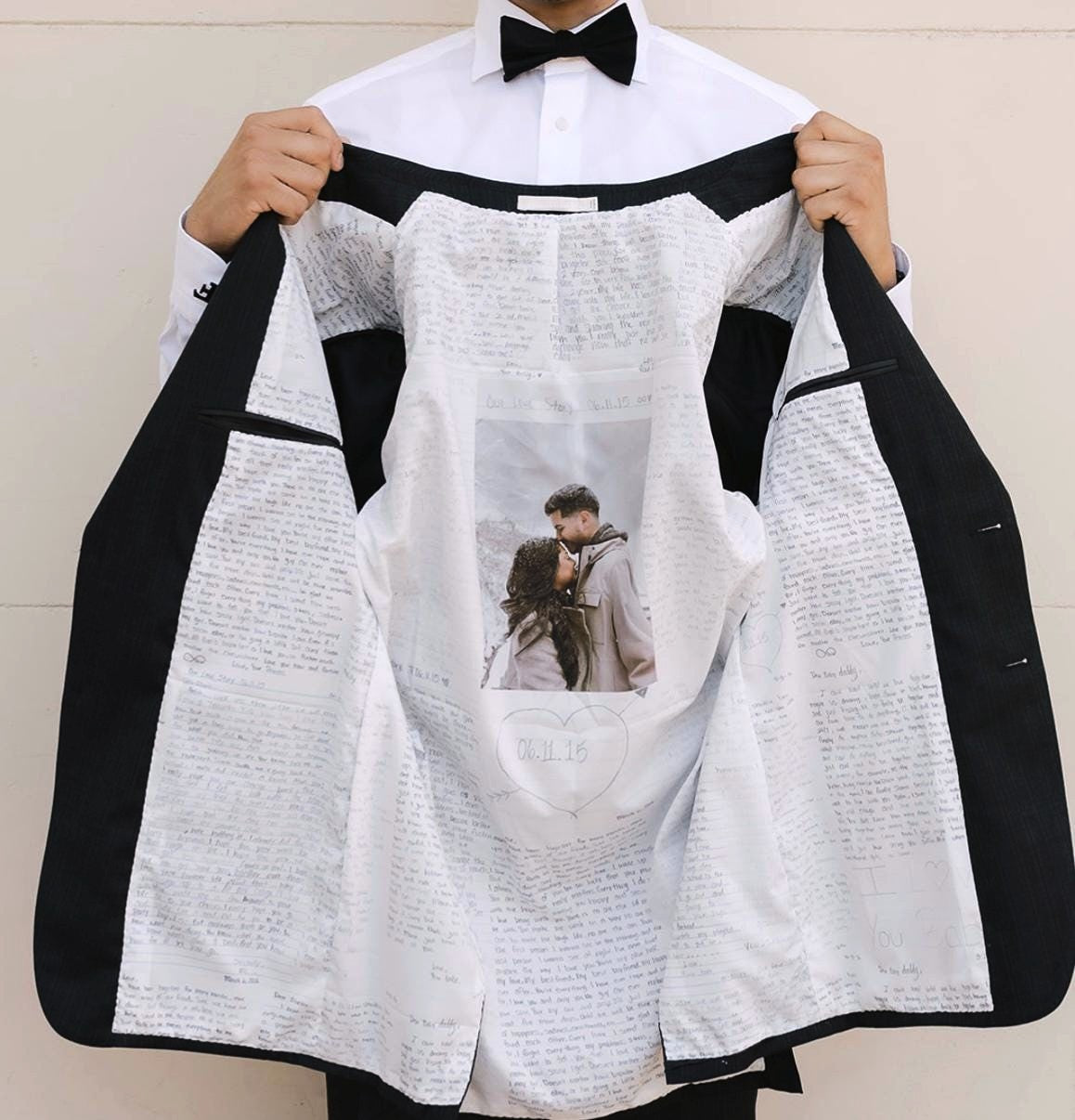 Person holding a black and white jacket with a printed design on a plain background