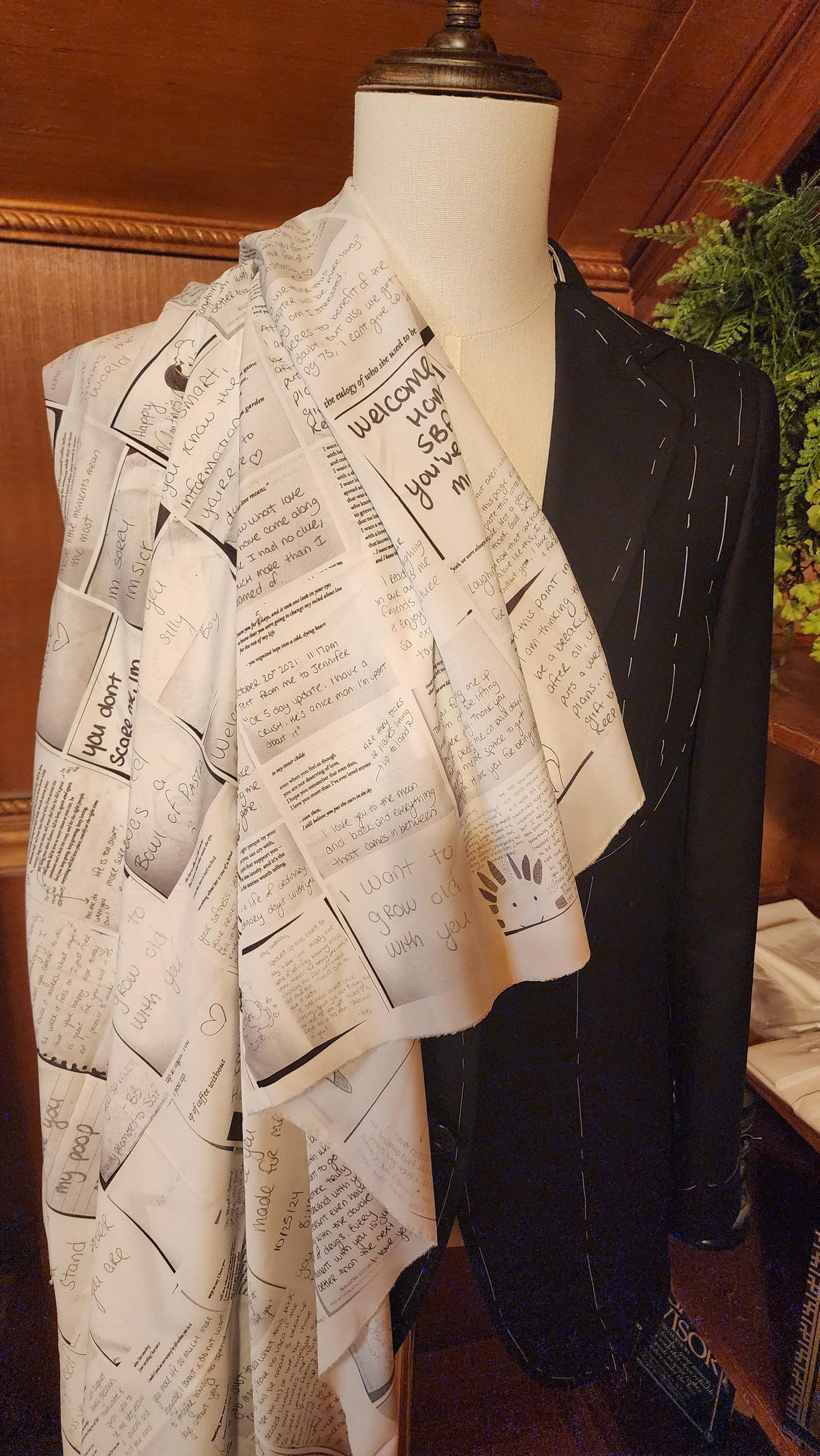 A mannequin displaying a custom suit lined with a collage of love notes and signatures, primarily in a white color range.