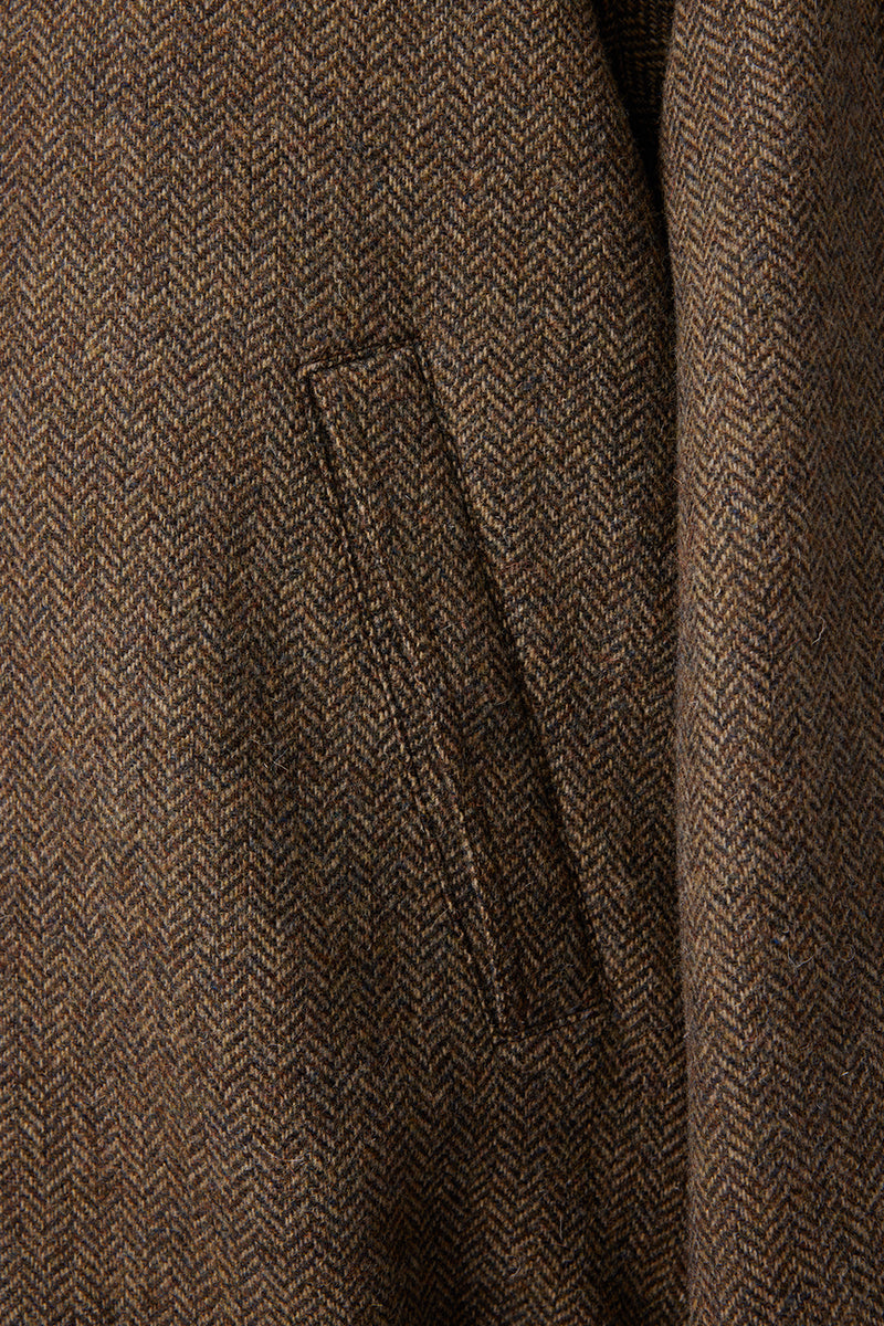 Close-up of a brown herringbone patterned fabric with a pocket detail.