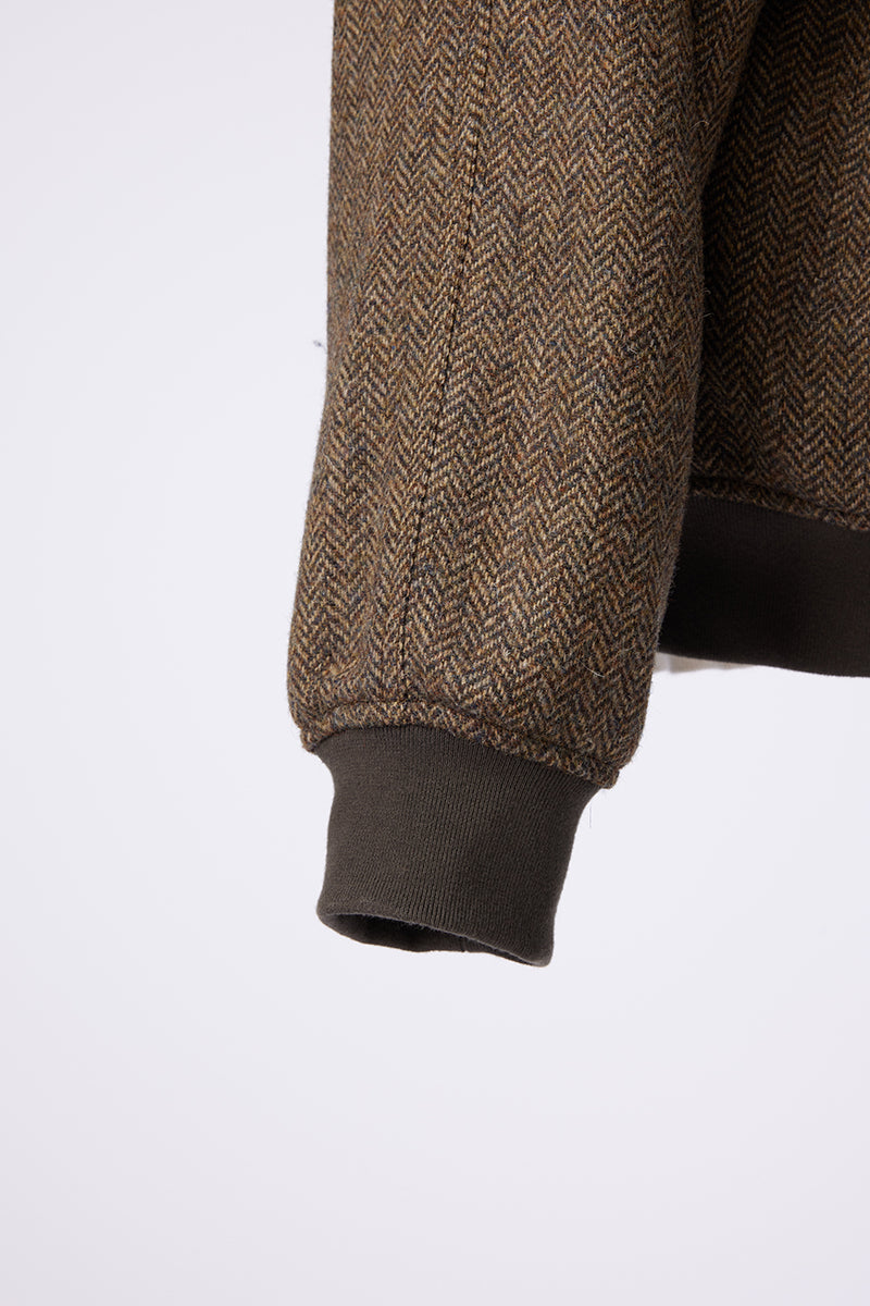 Close-up of a brown herringbone-patterned sleeve of a jacket with a white background