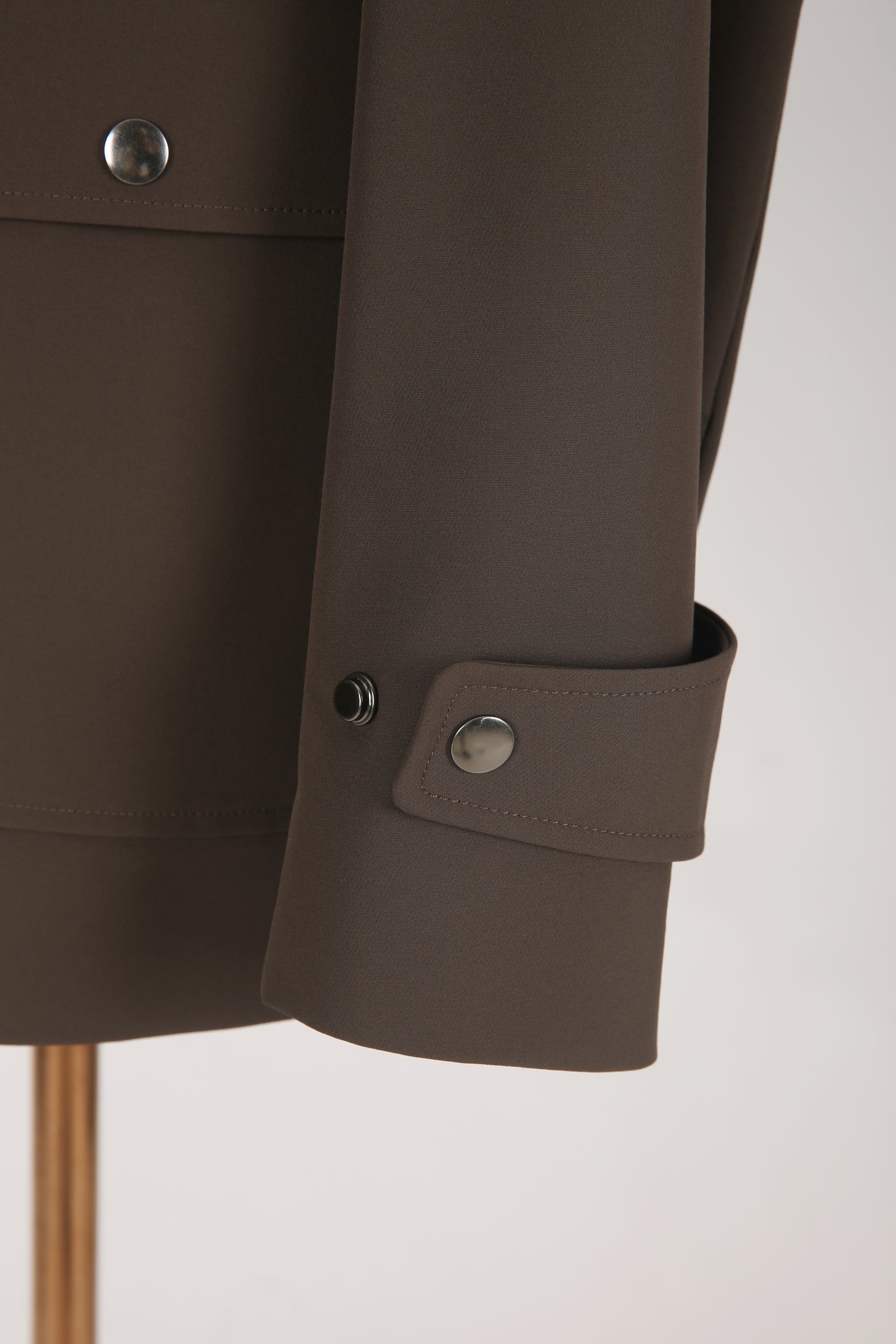 Close-up of a brown jacket with buttoned cuffs on a light gray background
