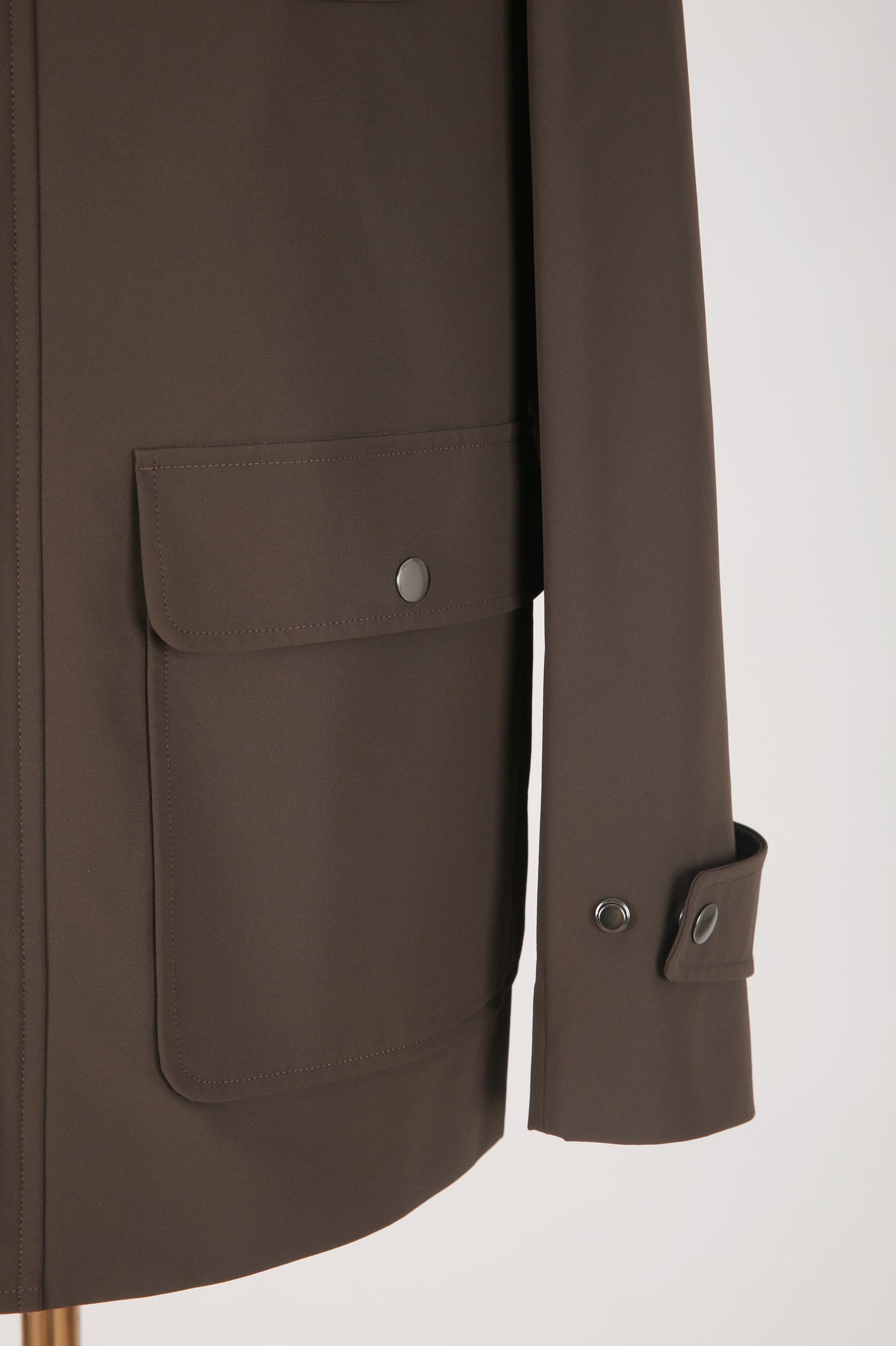 Brown coat with a pocket and button details on sleeve on a white background