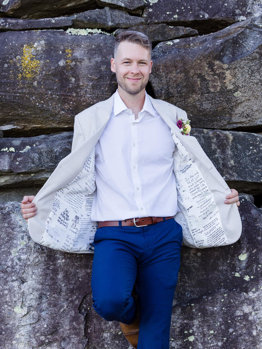 Man holding a large white jacket revealing love notes lining against a stone wall