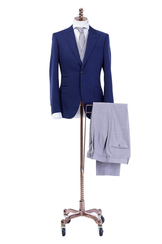 Blue wedding suit with peak lapel, a double breasted grey vest and grey pants. Blue and grey wedding suit. Blue wedding suit for groom. Grey wedding suit for groom. Blue suit with ticket pocket. Double breasted vest with shawl lapel.