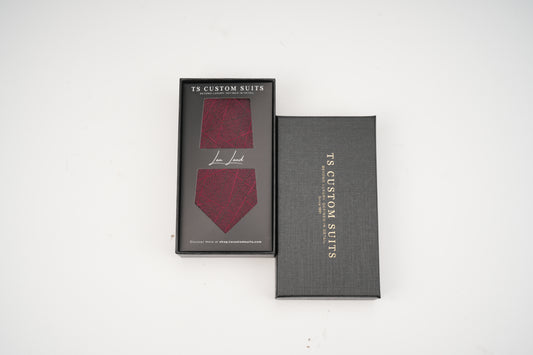 Maroon tie in a gray box with 'TS Custom Suits' branding on a white background