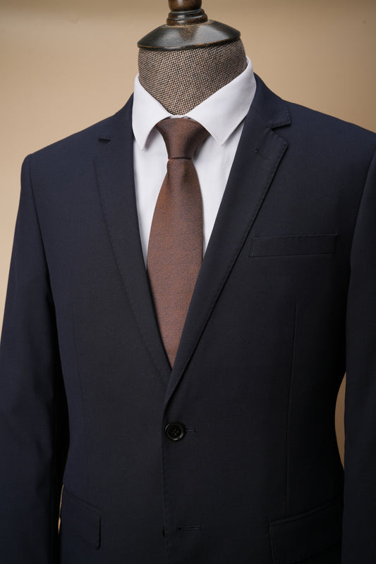Dark suit jacket with a white shirt and brown tie on a mannequin against a beige background