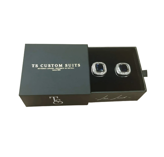 Cufflinks in a 'TS Custom Suits' box on a light beige background