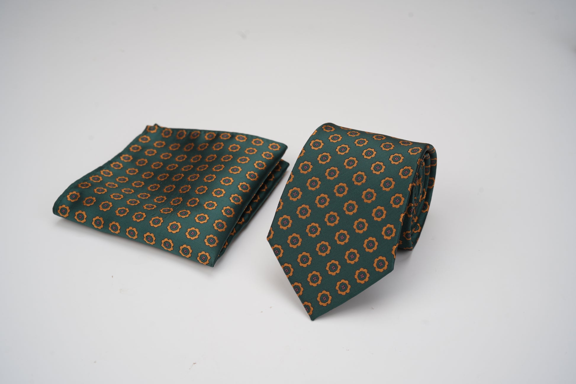 Green patterned tie and pocket square on a white background