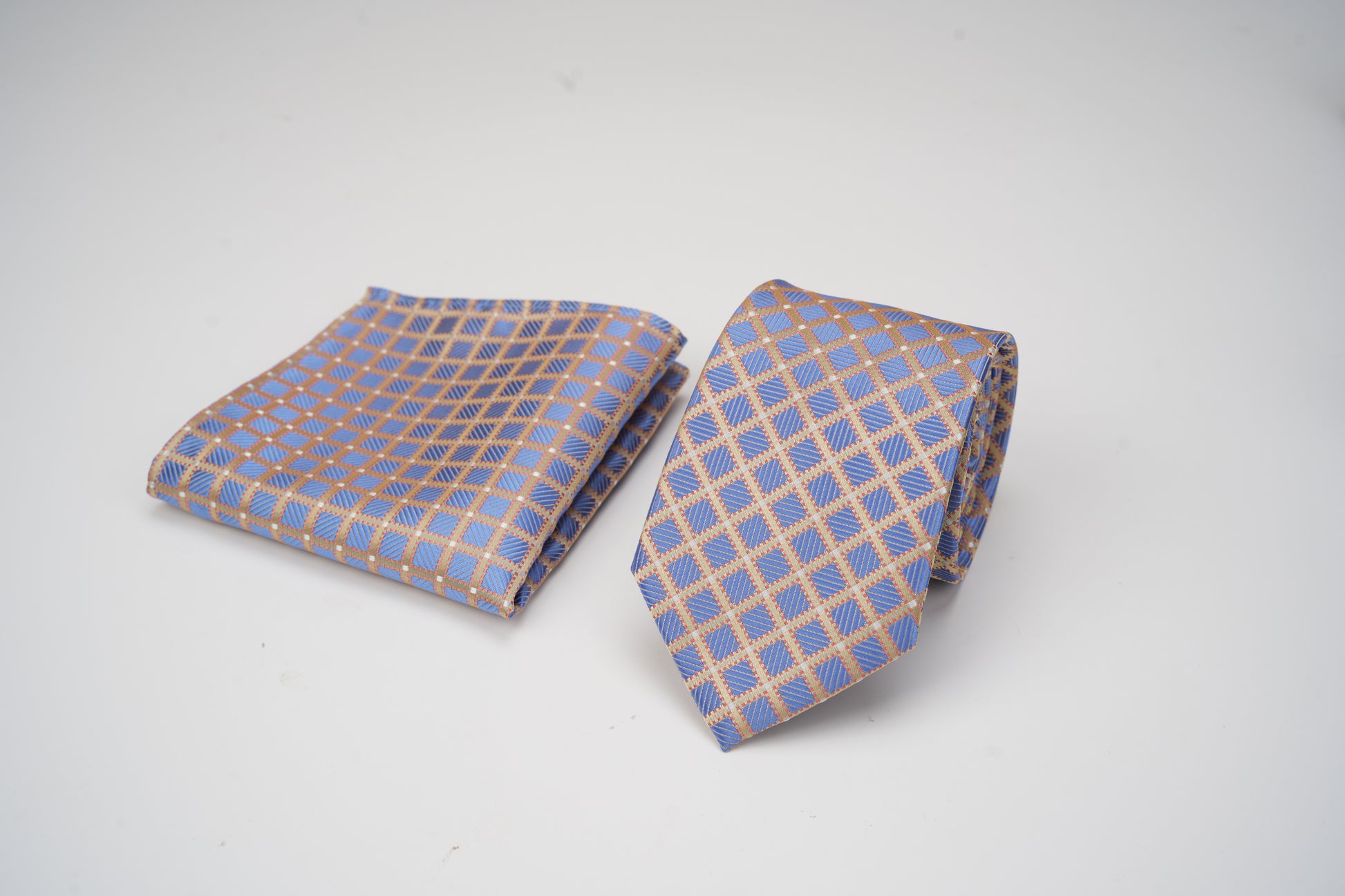 Blue and beige checkered tie and pocket square on a white background