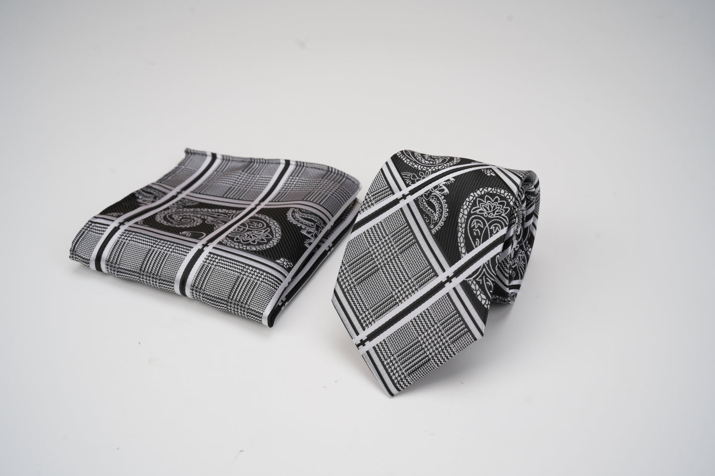 Black and white patterned tie and pocket square on a light gray background