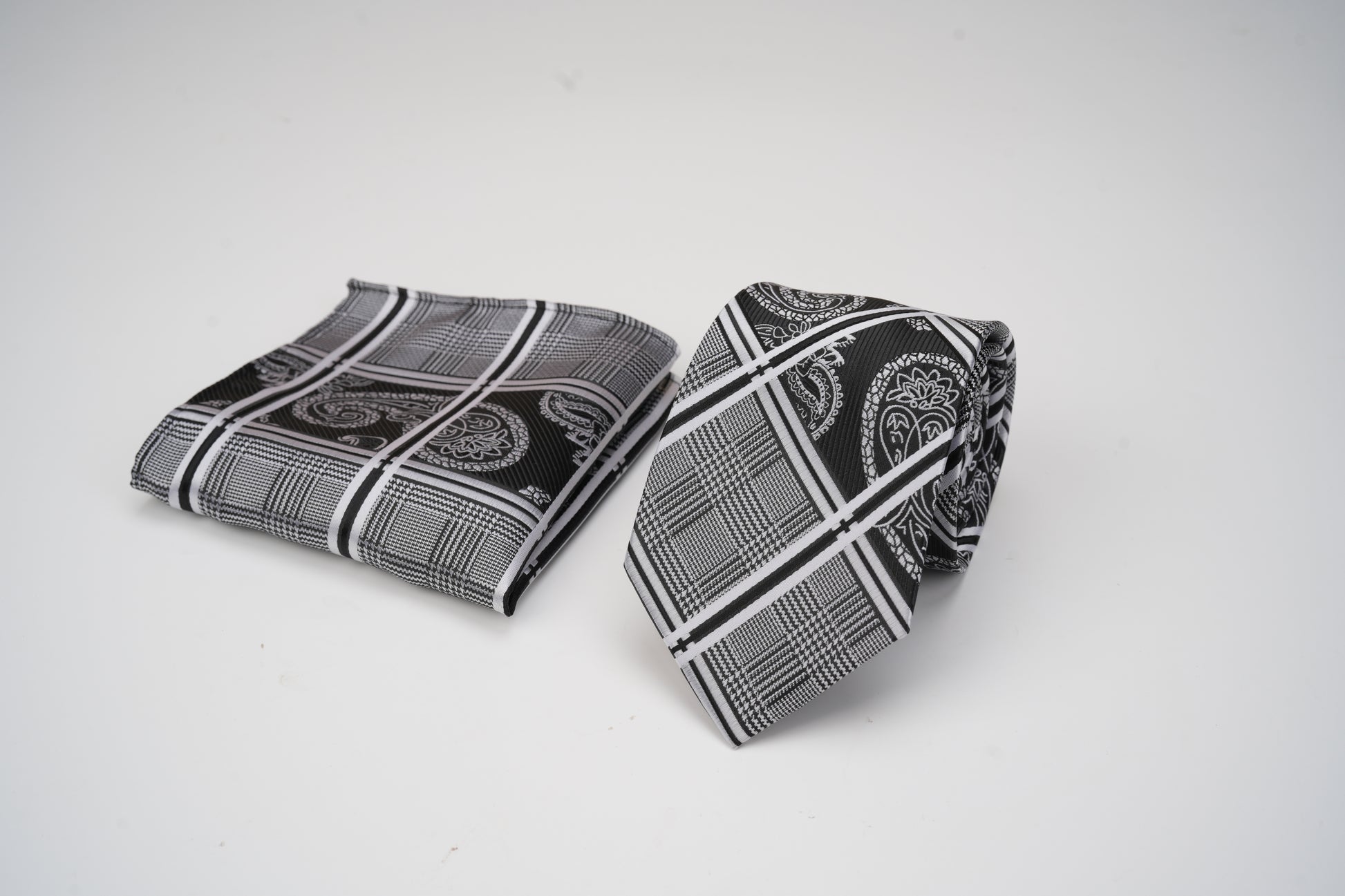 Black and white patterned tie and pocket square on a light gray background
