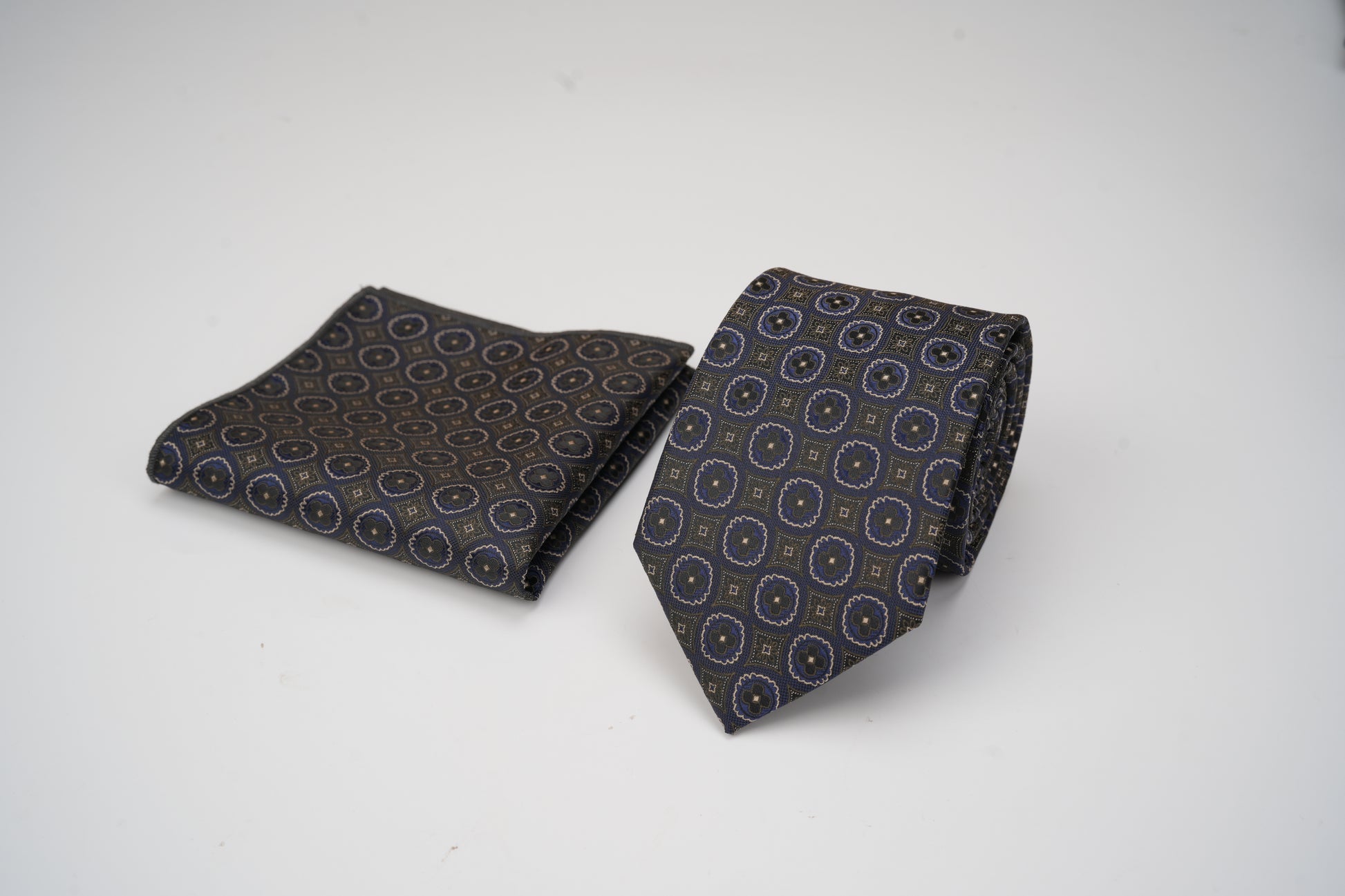Black patterned tie and pocket square on a white background