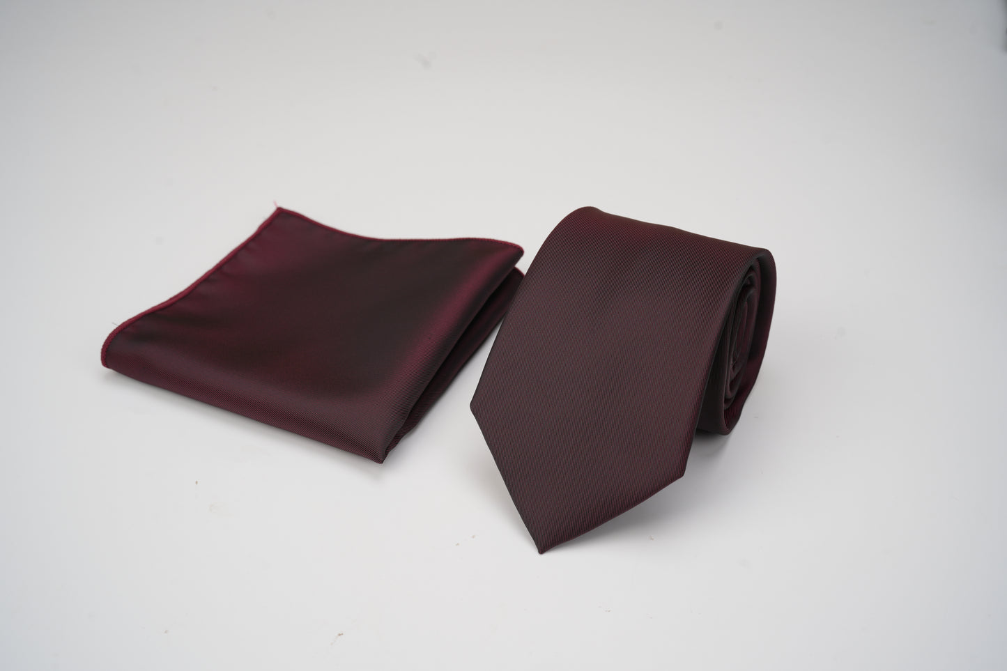Burgundy tie and pocket square set on a white background