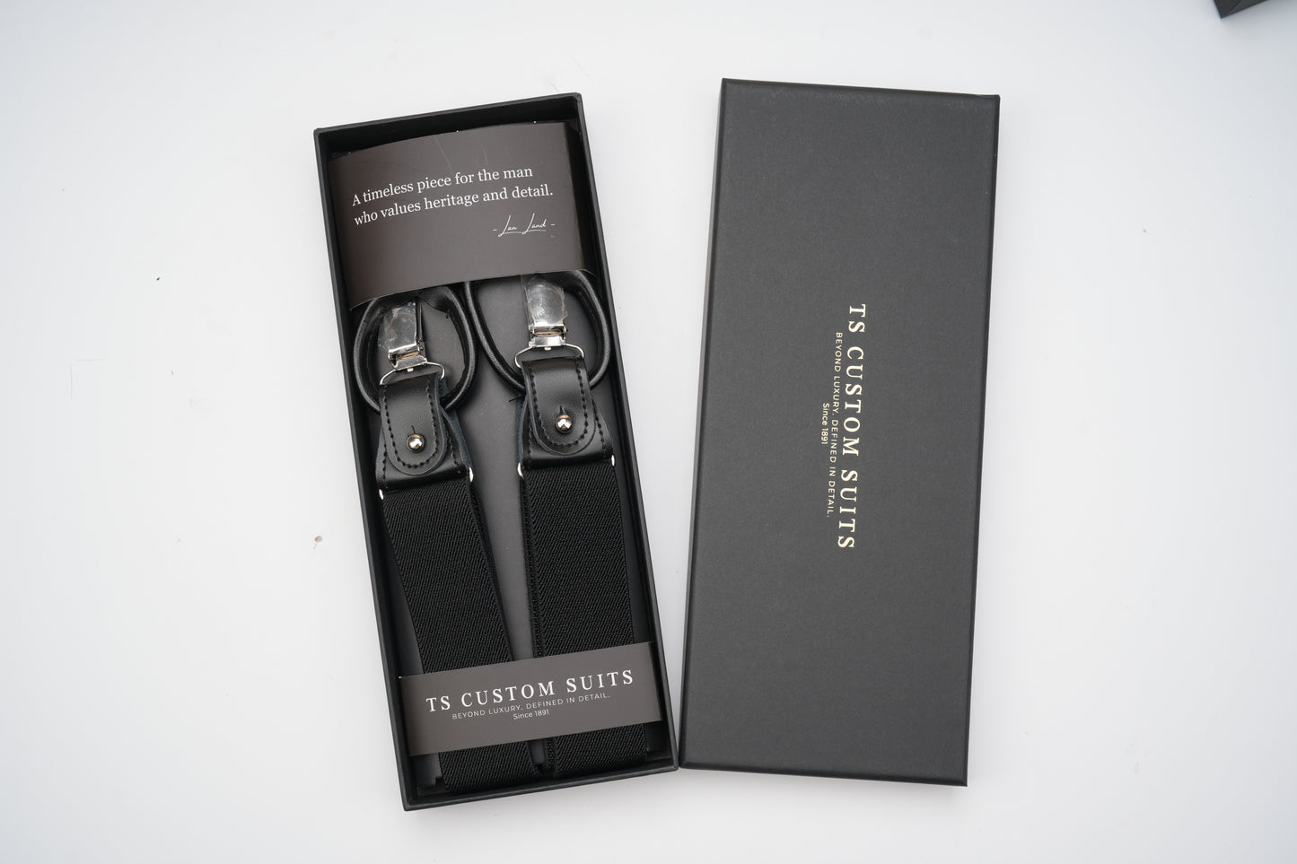 Black suspenders in a branded box on a white background