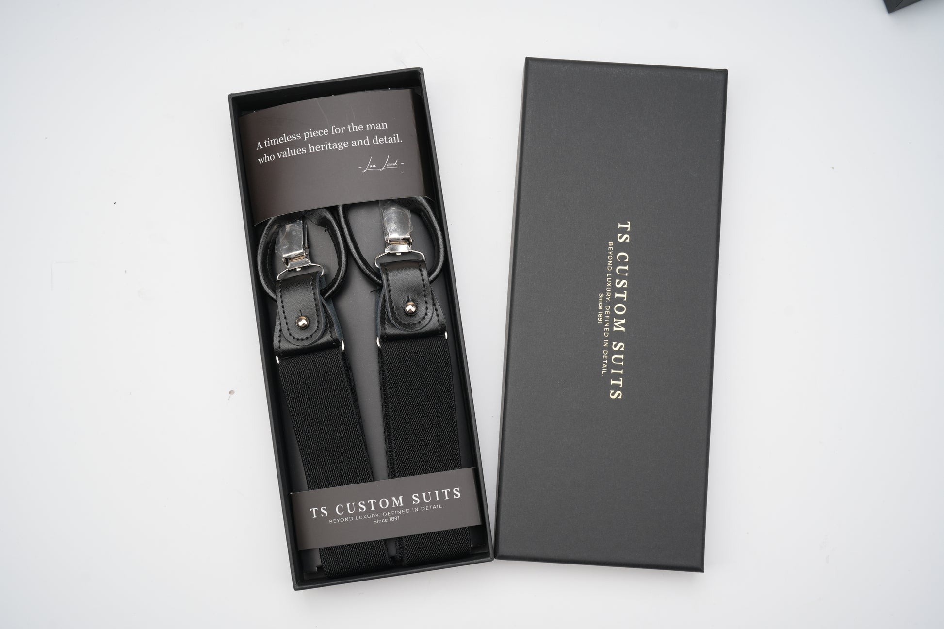 Black suspenders in a branded box on a white background