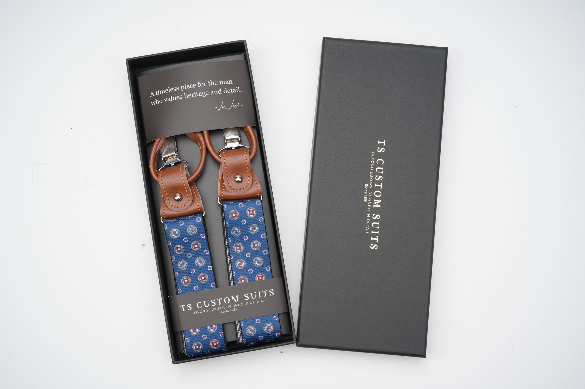 Blue patterned suspenders in a black box with 'TS Custom Suits' branding.