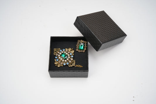 Pair of ornate earrings with gemstones in a black jewelry box on a white background