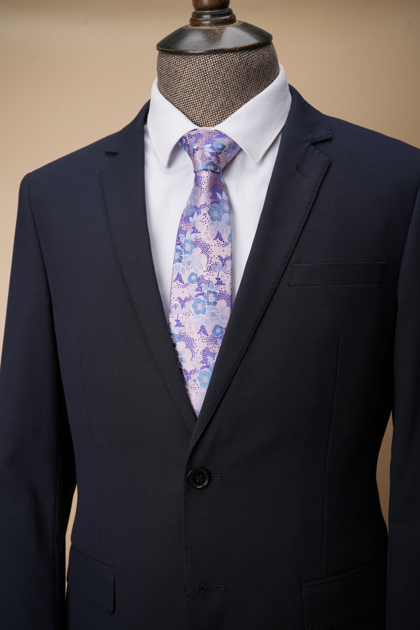 Navy suit jacket with a white shirt and floral tie on a beige background