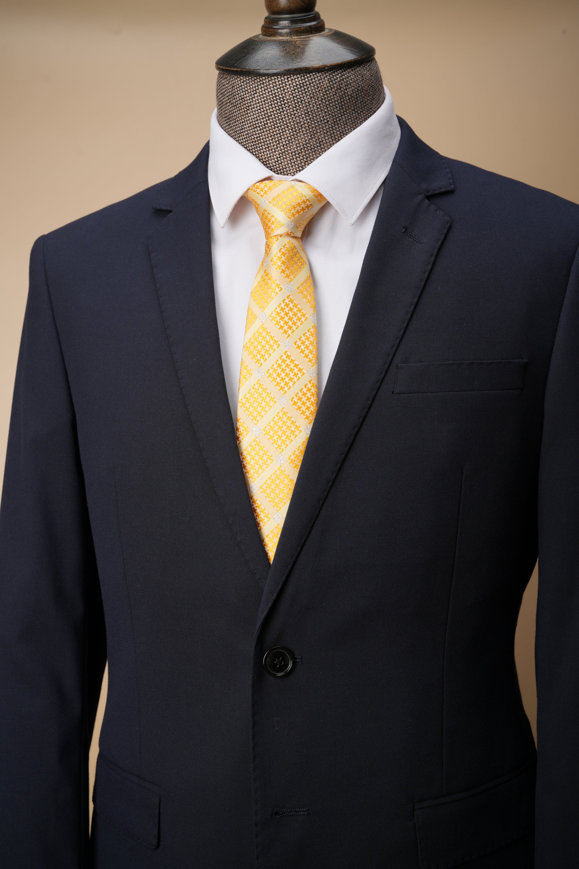 Yellow patterned tie on a mannequin with a dark suit jacket.