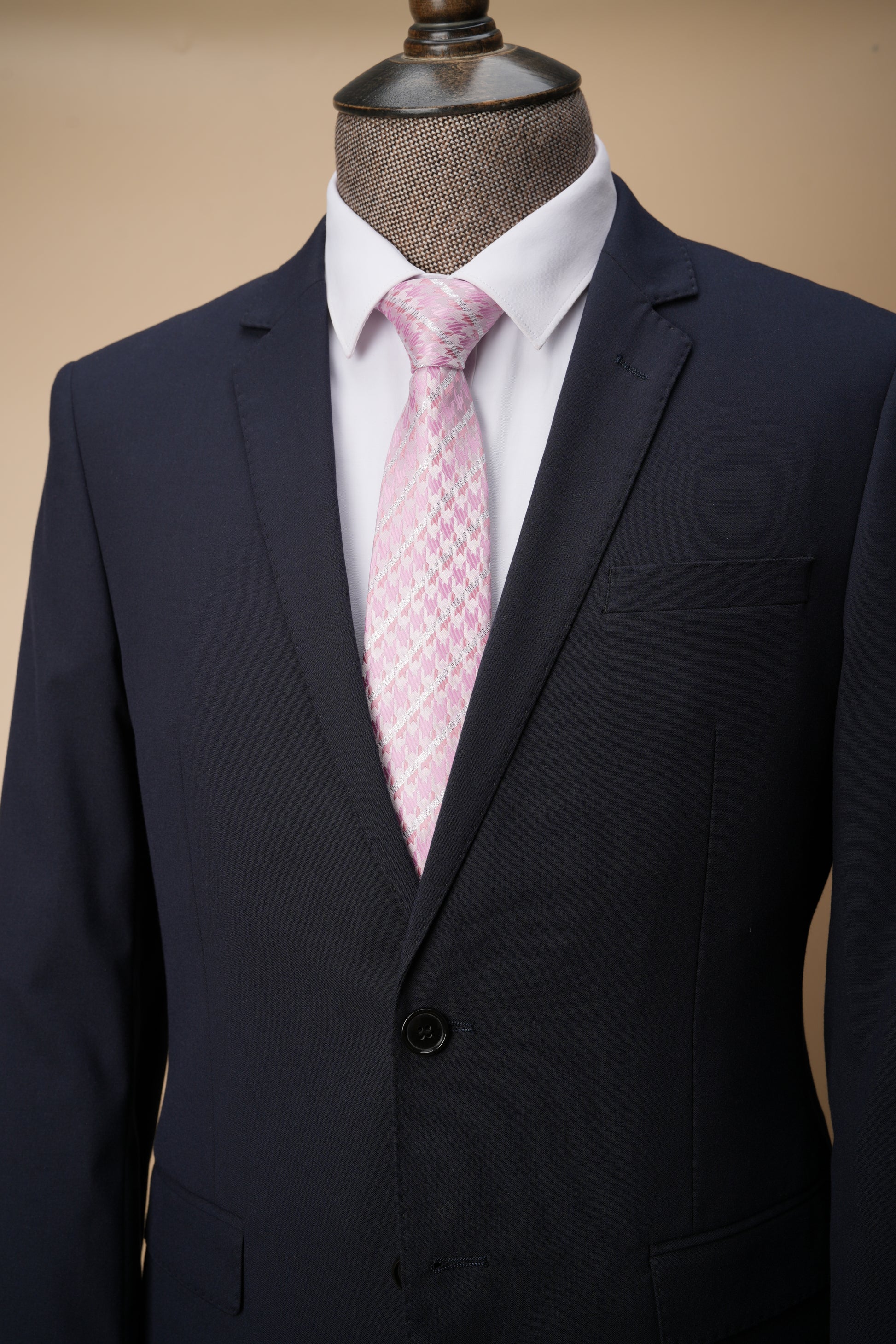 Navy suit jacket with a pink patterned tie on a mannequin against a beige background