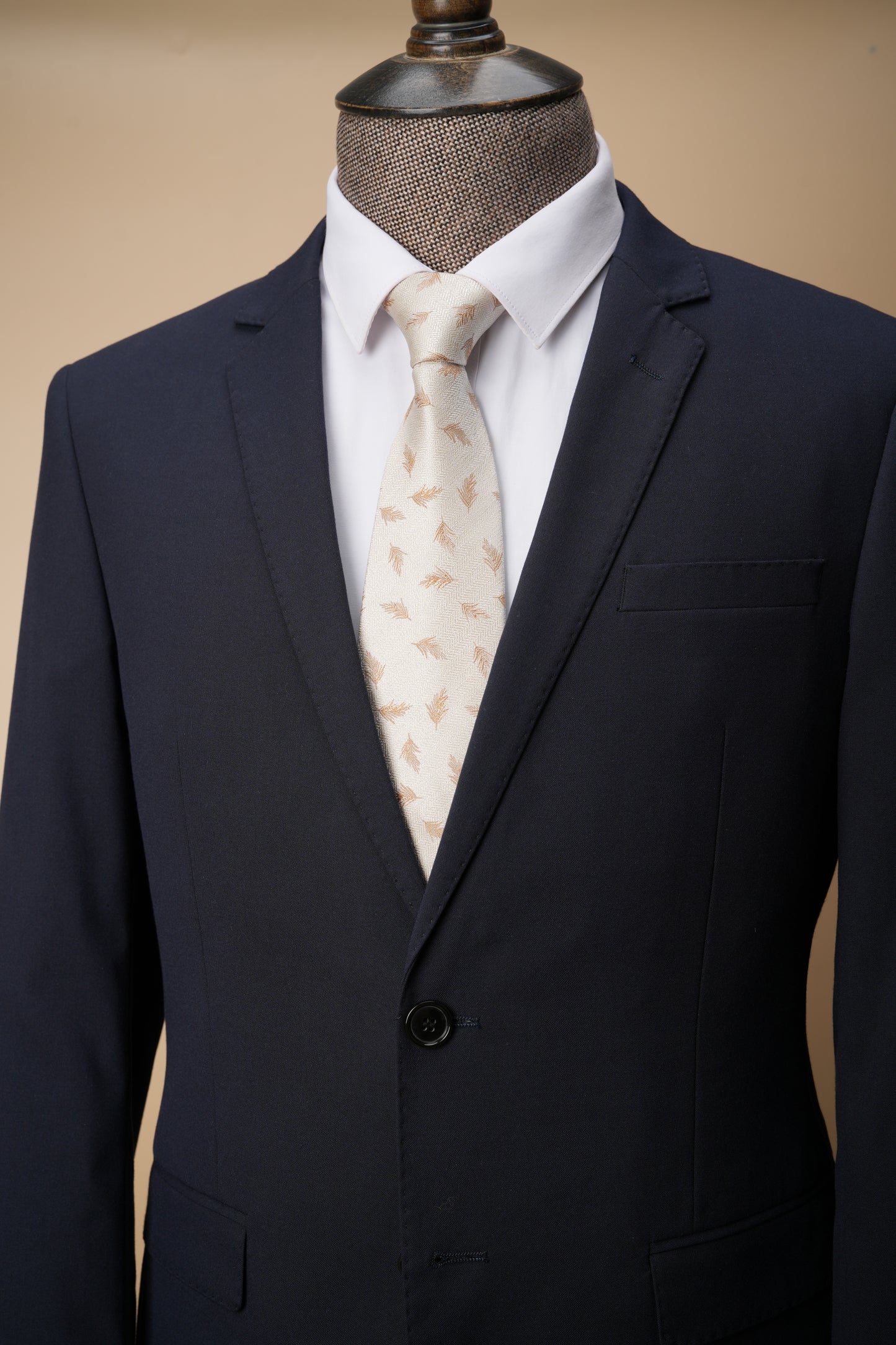 Navy suit jacket with a white shirt and patterned tie on a beige background