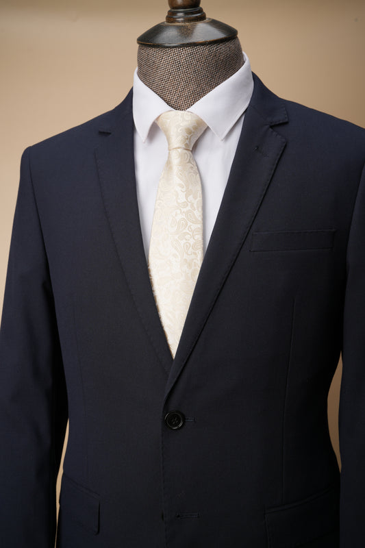 Navy suit jacket with white shirt and patterned tie on a mannequin against a beige background
