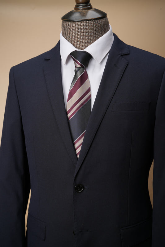 Navy suit jacket with a striped tie on a mannequin against a beige background