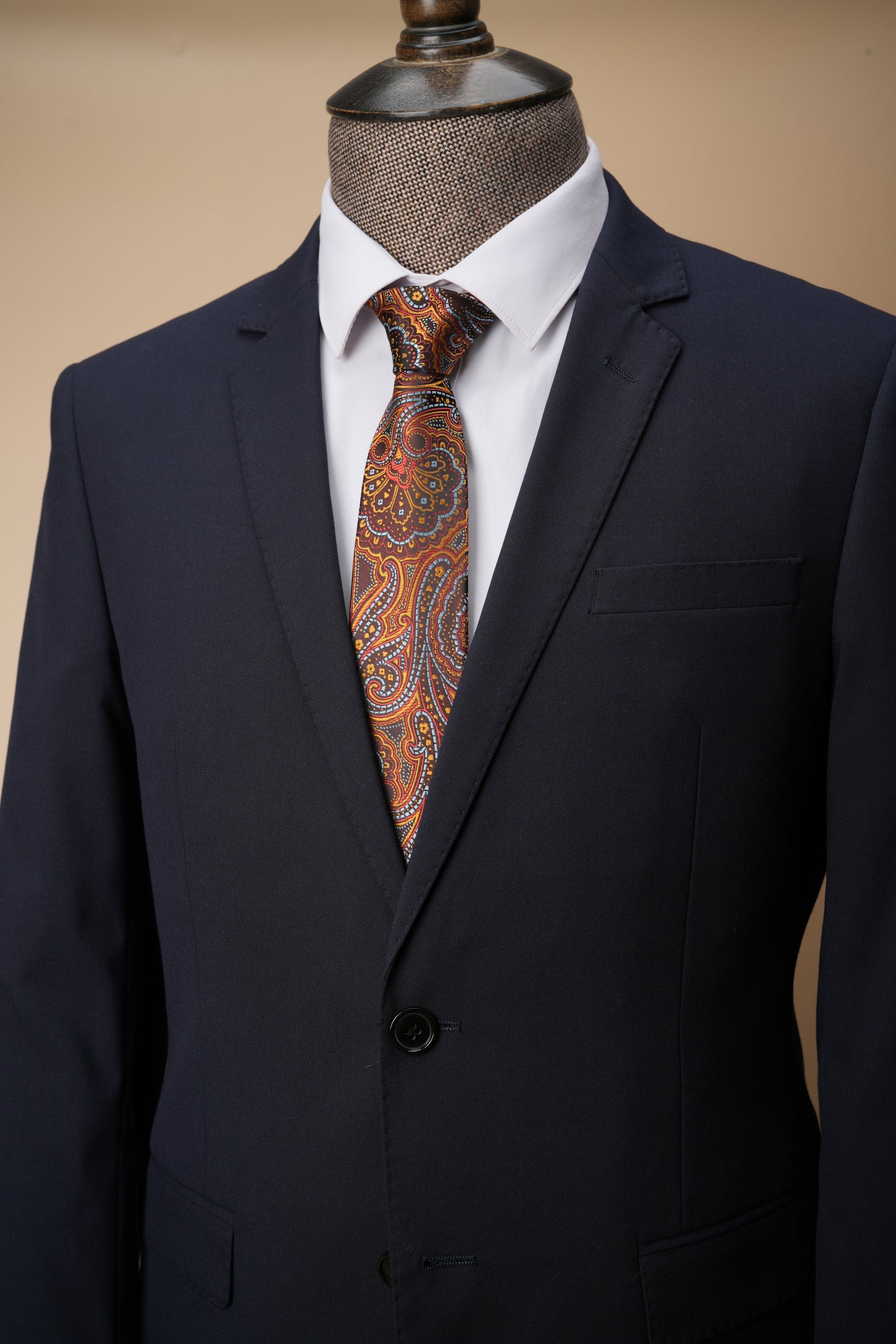 Black suit jacket with a patterned tie in the pocket on a beige background