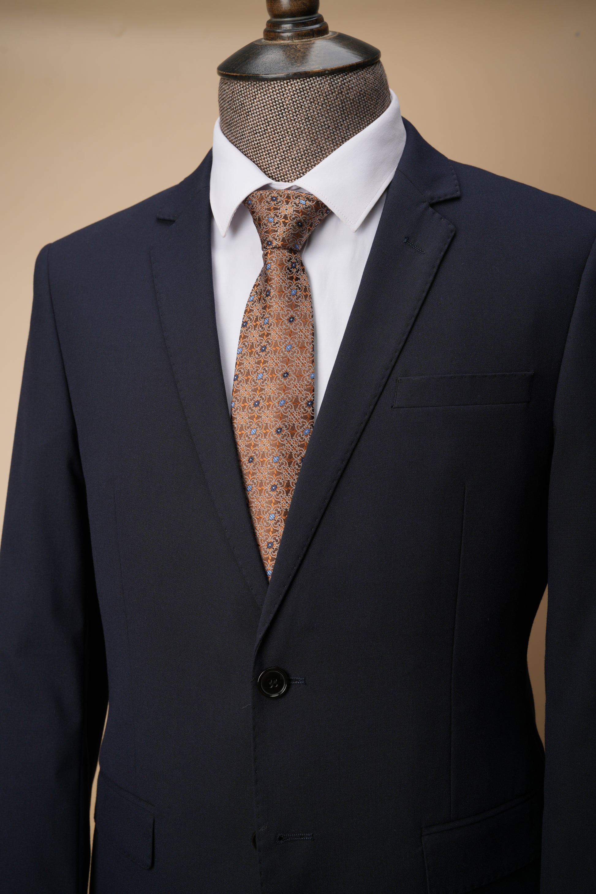 Black suit jacket with a white shirt and patterned tie on a beige background