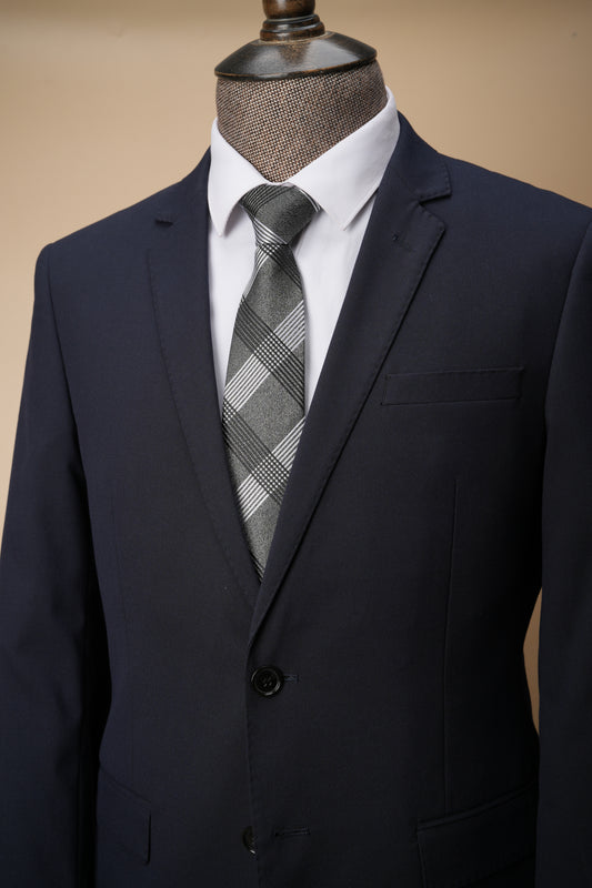Navy suit jacket with a plaid tie on a mannequin against a beige background