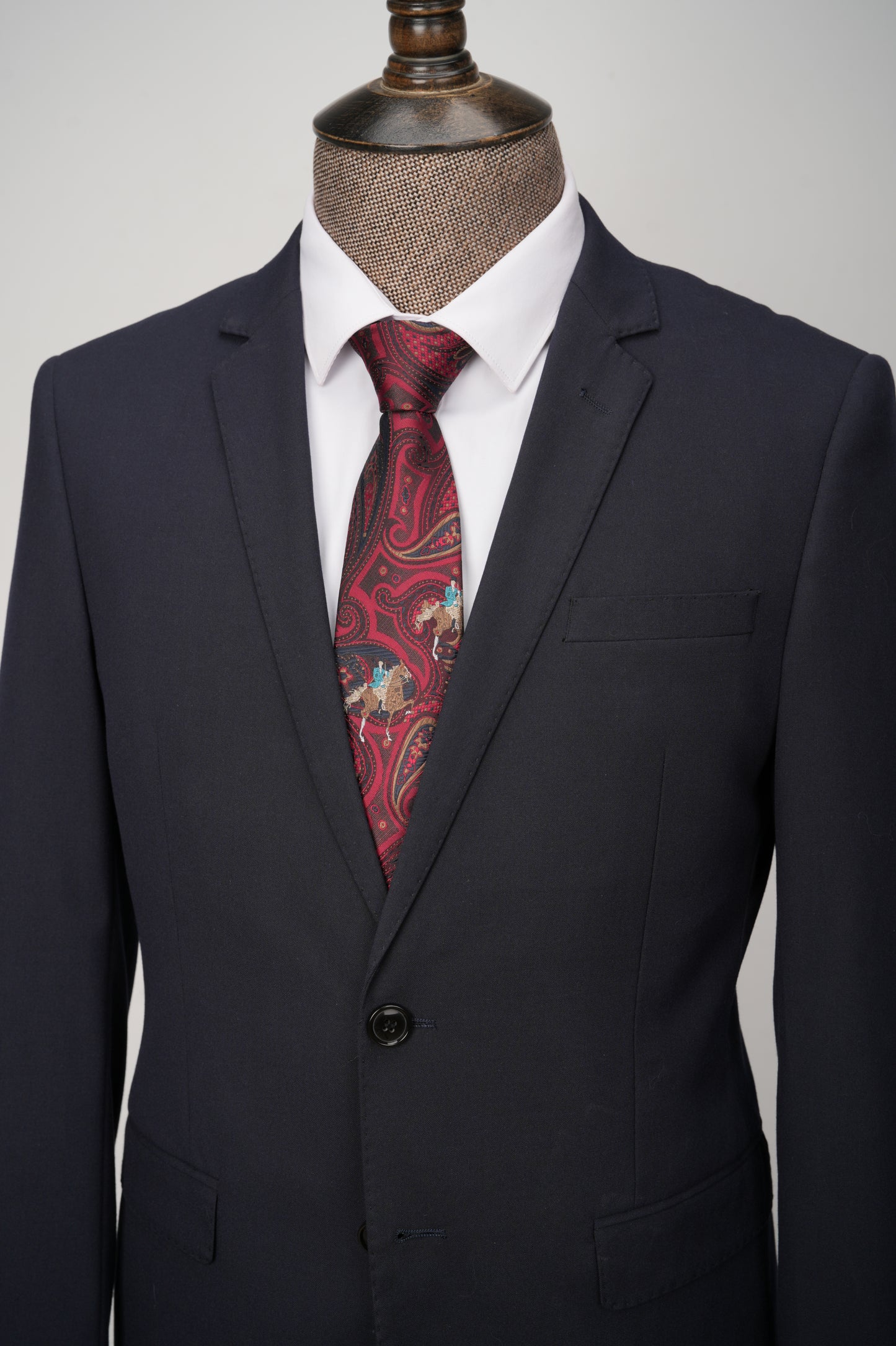 Black suit jacket with a red paisley tie on a mannequin against a gray background