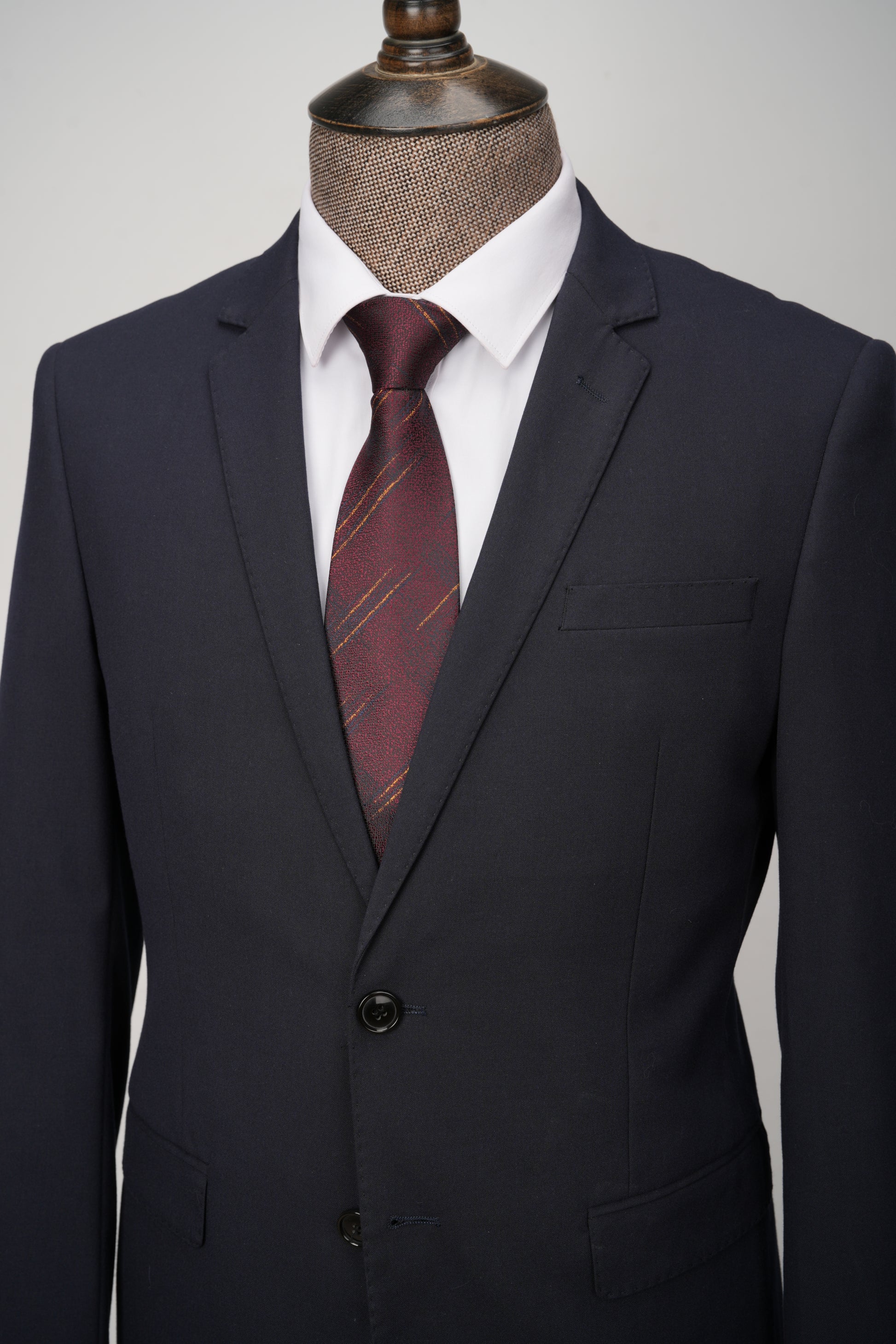 Navy suit with a red striped tie on a mannequin against a gray background