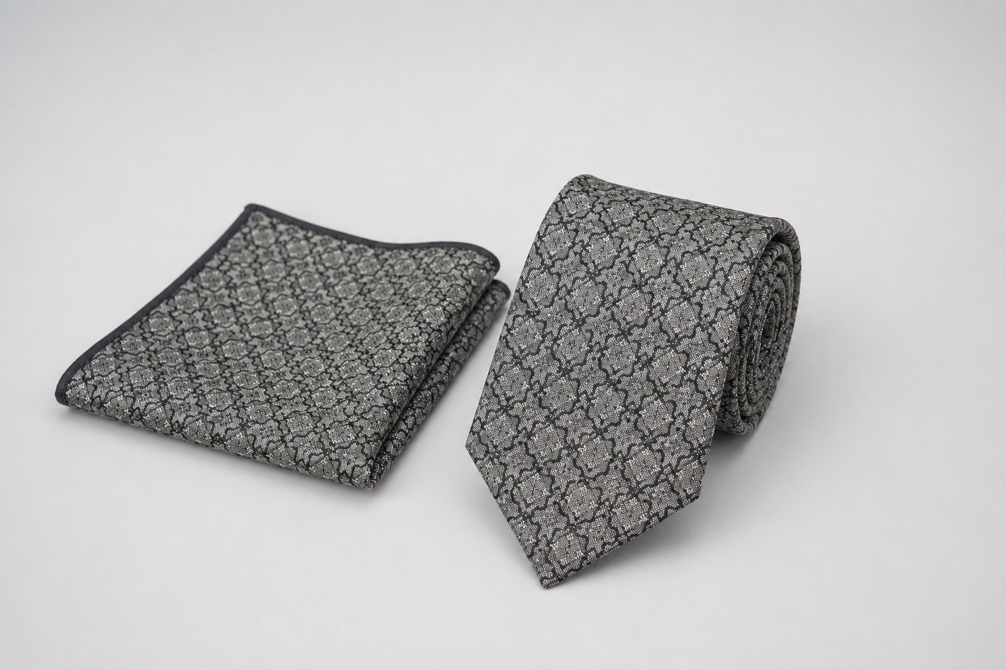 Gray patterned tie and pocket square on a light gray background