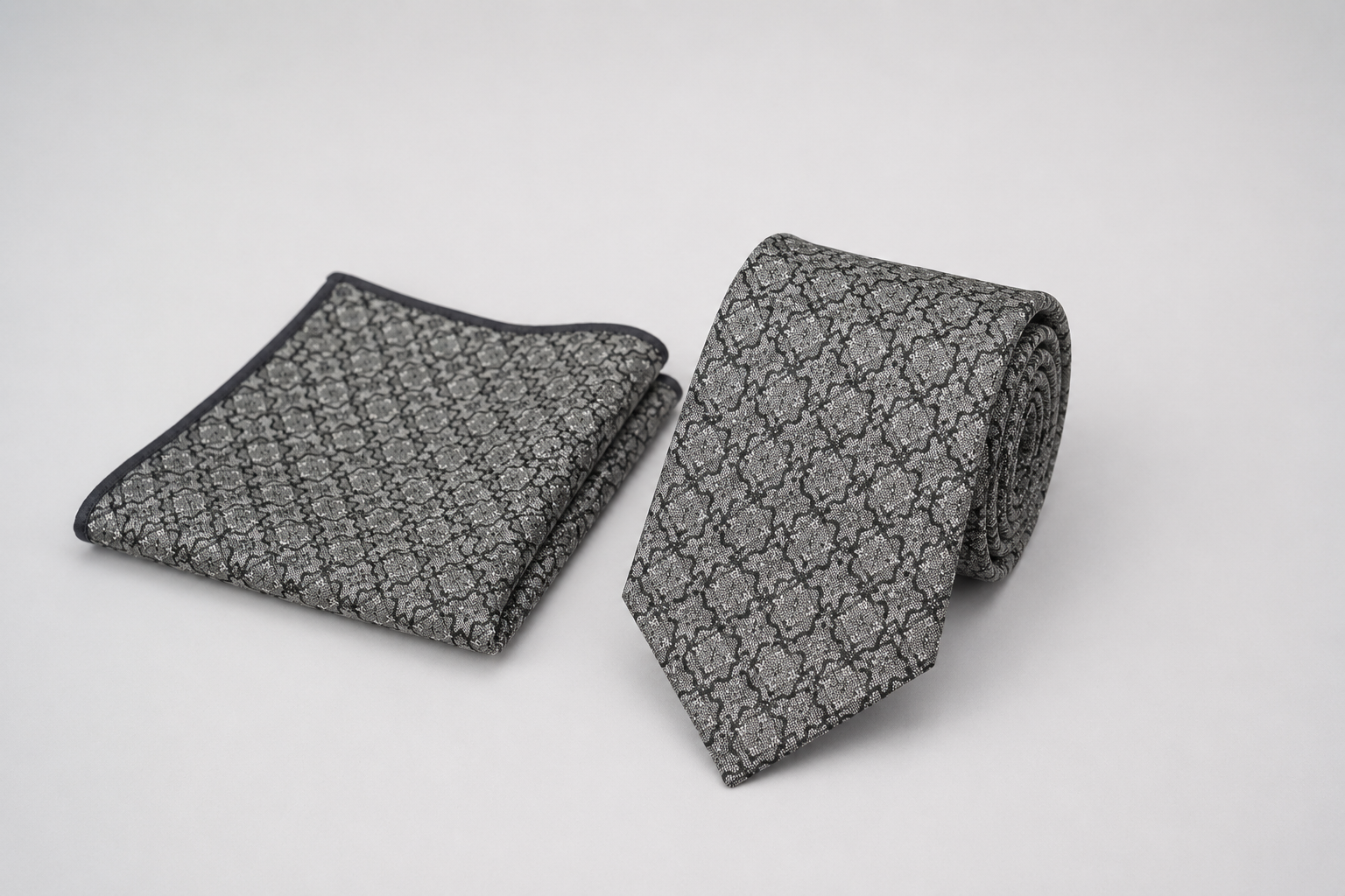 Gray patterned tie and pocket square on a light gray background
