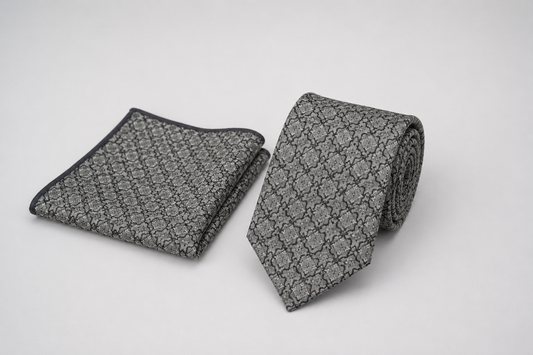 Gray patterned tie and pocket square on a light gray background