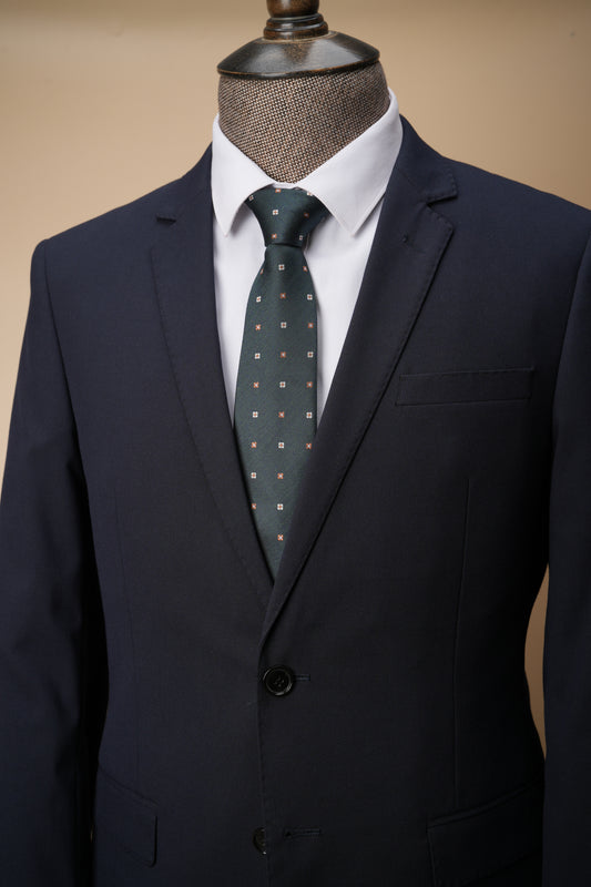 Navy suit with a white shirt and green patterned tie on a mannequin against a beige background