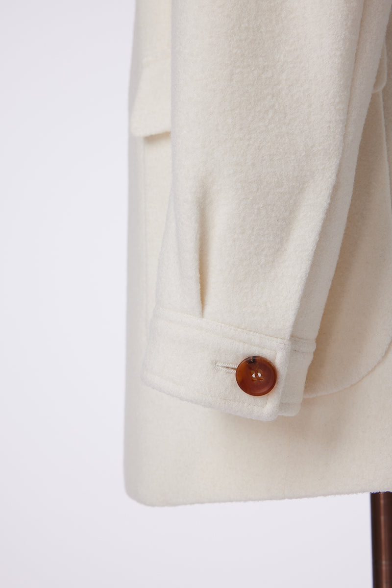 Close-up of a beige blazer with a button on a white background
