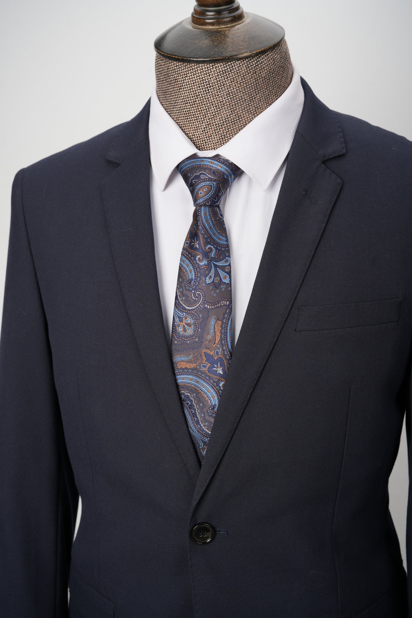 Navy suit jacket with a patterned tie peeking out from the pocket on a mannequin.