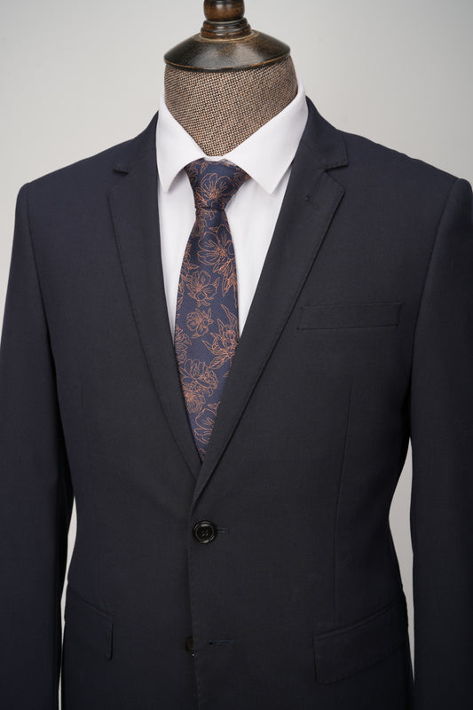Black suit jacket with a white shirt and patterned tie on a mannequin against a gray background
