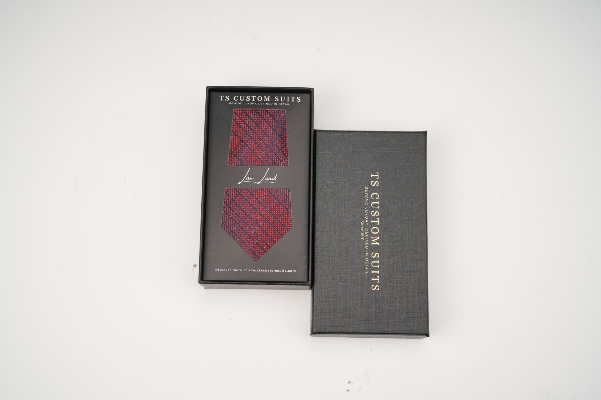 Red patterned tie in a 'TS Custom Suits' box on a white background