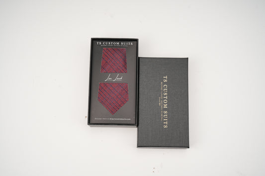 Red patterned tie in a 'TS Custom Suits' box on a white background
