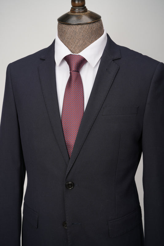 Dark gray suit with a red patterned tie on a mannequin against a light gray background