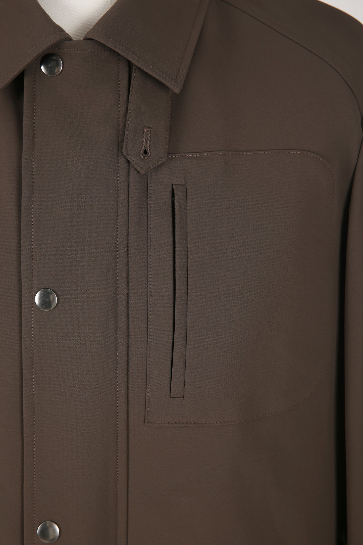 Close-up of a brown jacket with buttons and a pocket