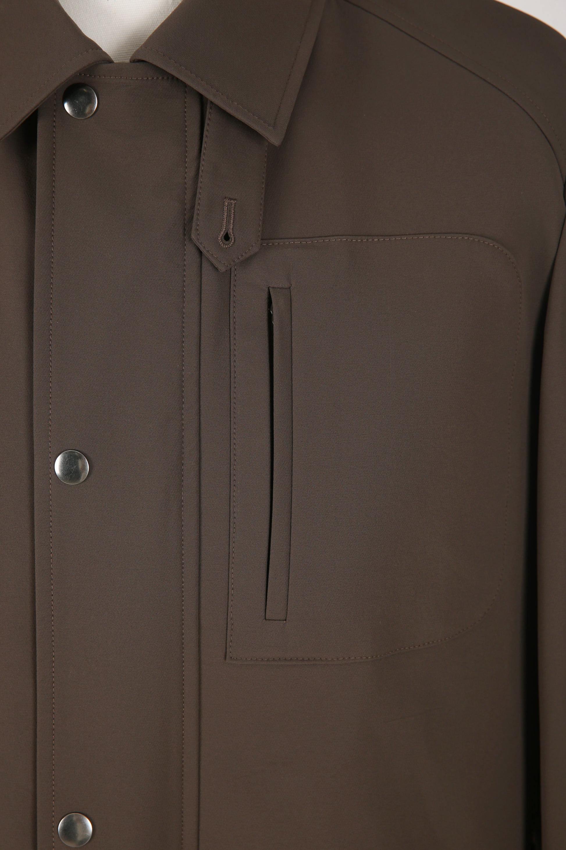 Close-up of a brown jacket with buttons and a pocket