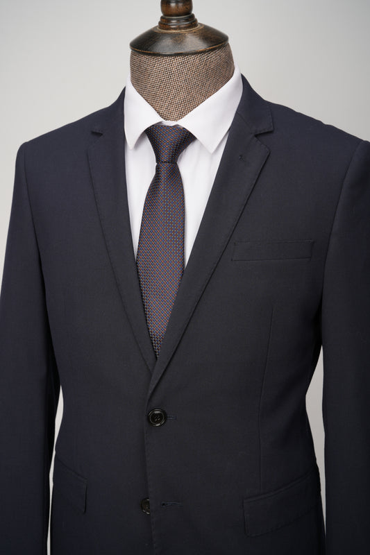 Dark gray suit with a white shirt and patterned tie on a mannequin against a light gray background