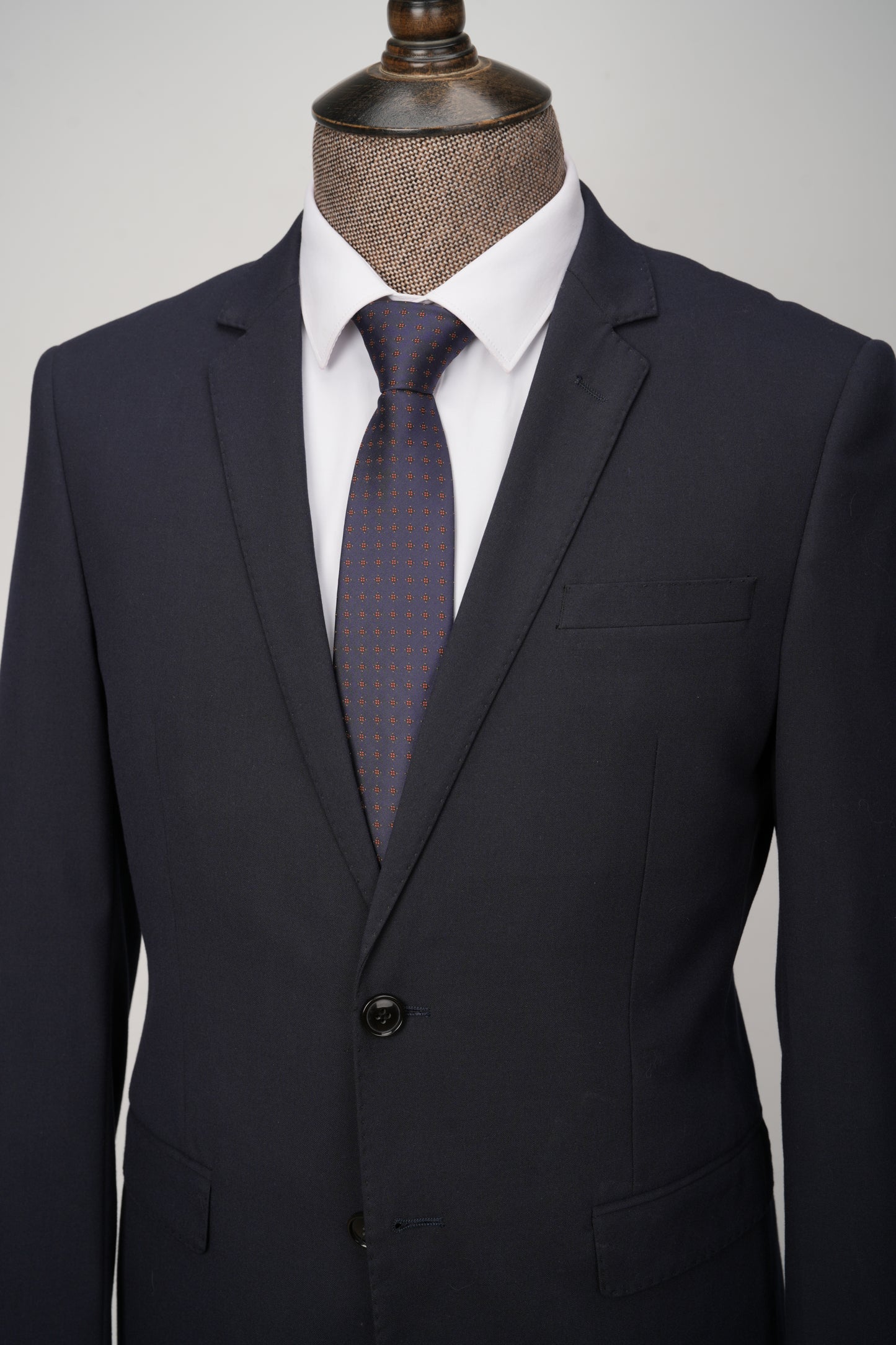 Dark suit with a patterned tie on a mannequin against a gray background