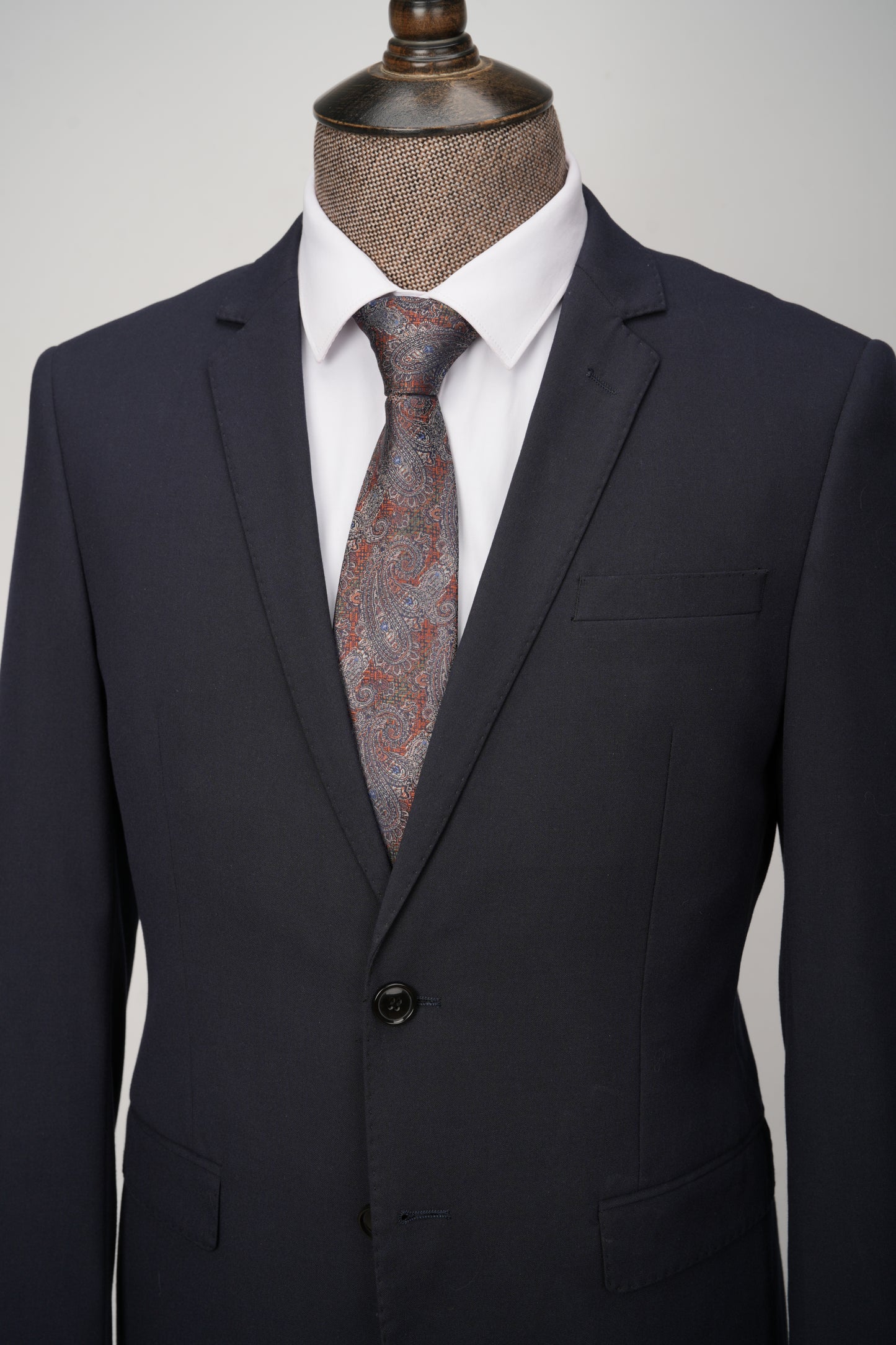 Navy suit jacket with a patterned tie on a mannequin against a neutral background